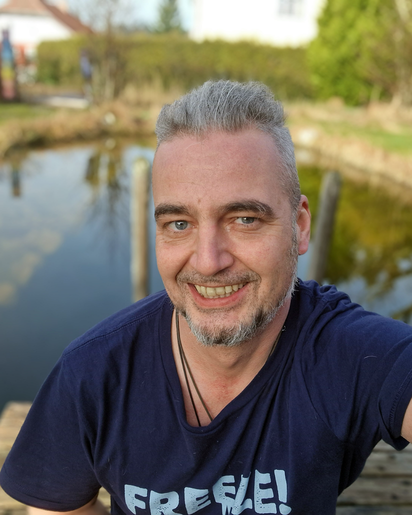 A relaxed man in front of a natural swimming pond